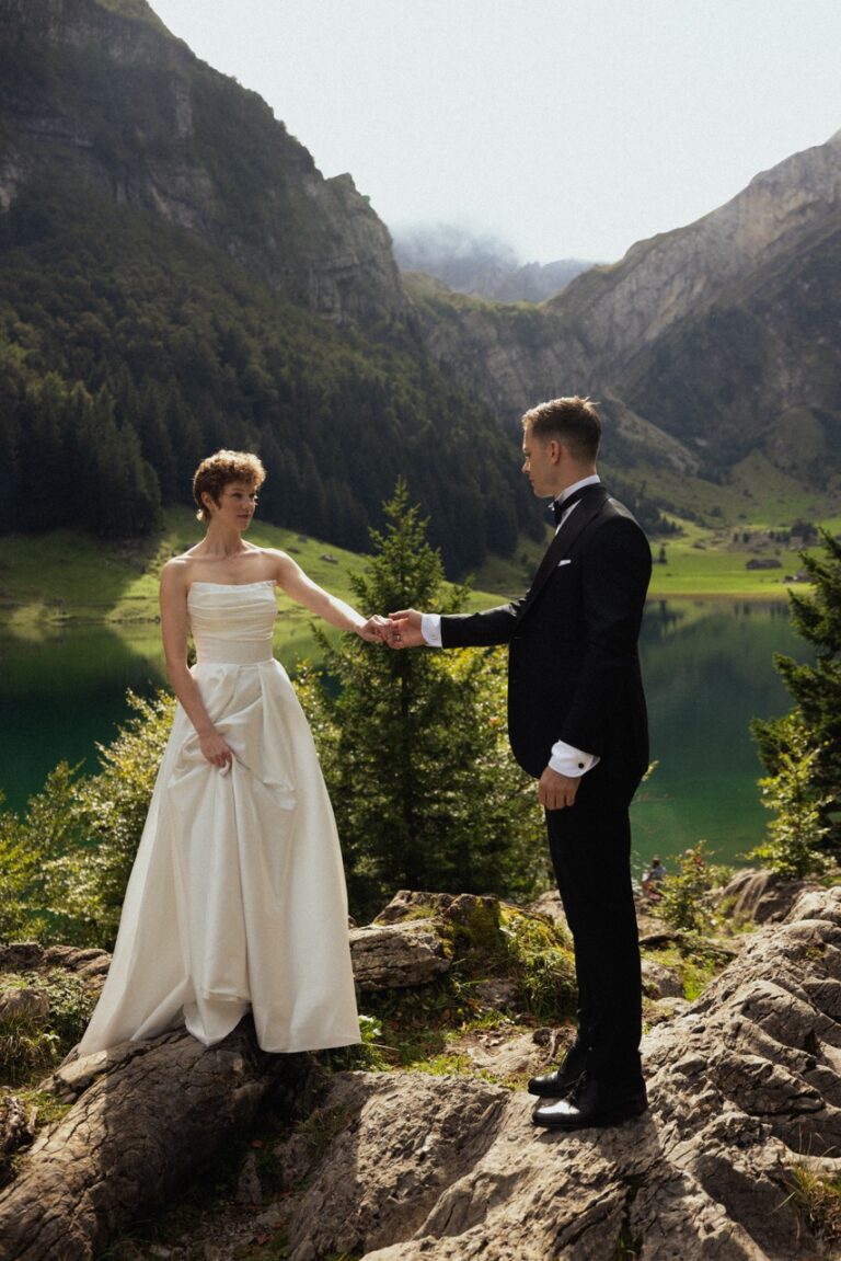 bride and groom holding each other hand with mountain and lake behind them