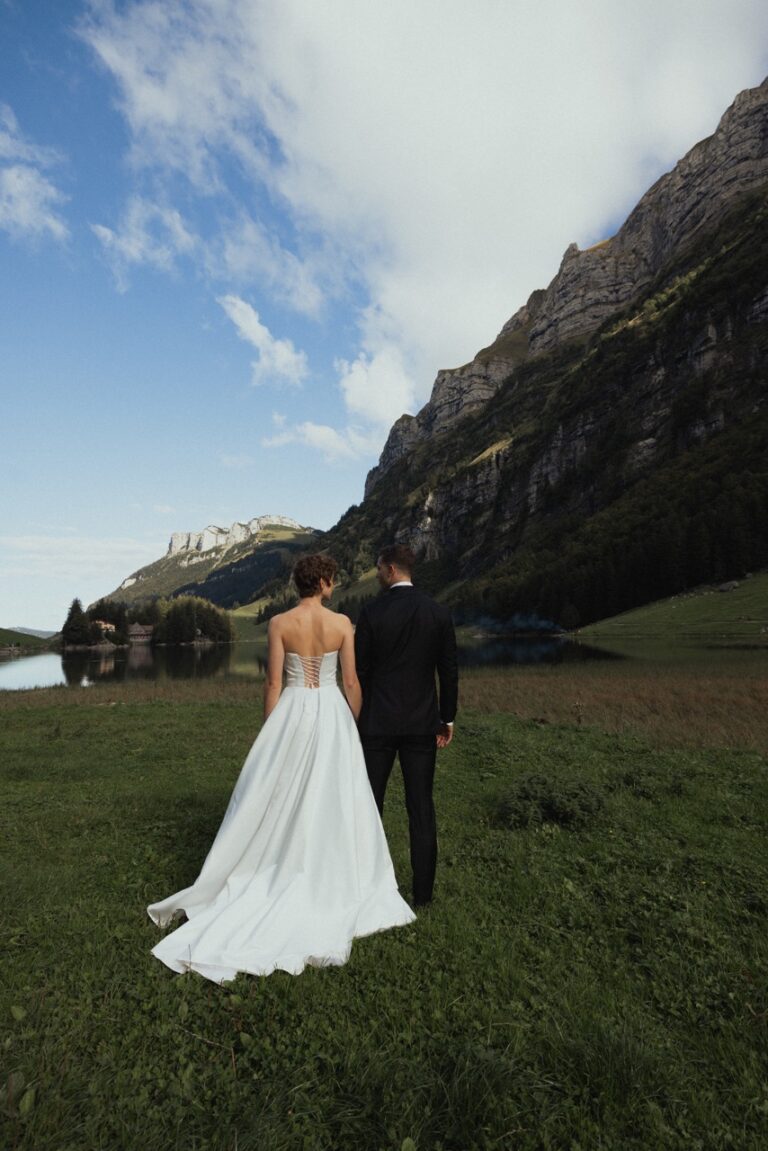 picture of the behind of the bride and groom with mountain and lake